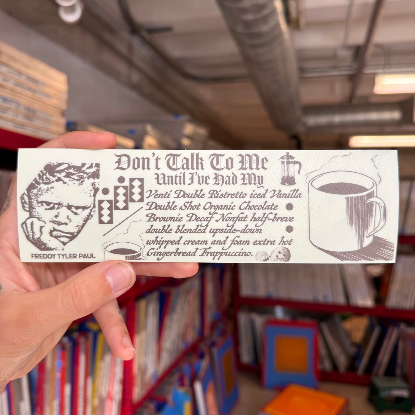 Hand holding a card with text and graphics in a library setting