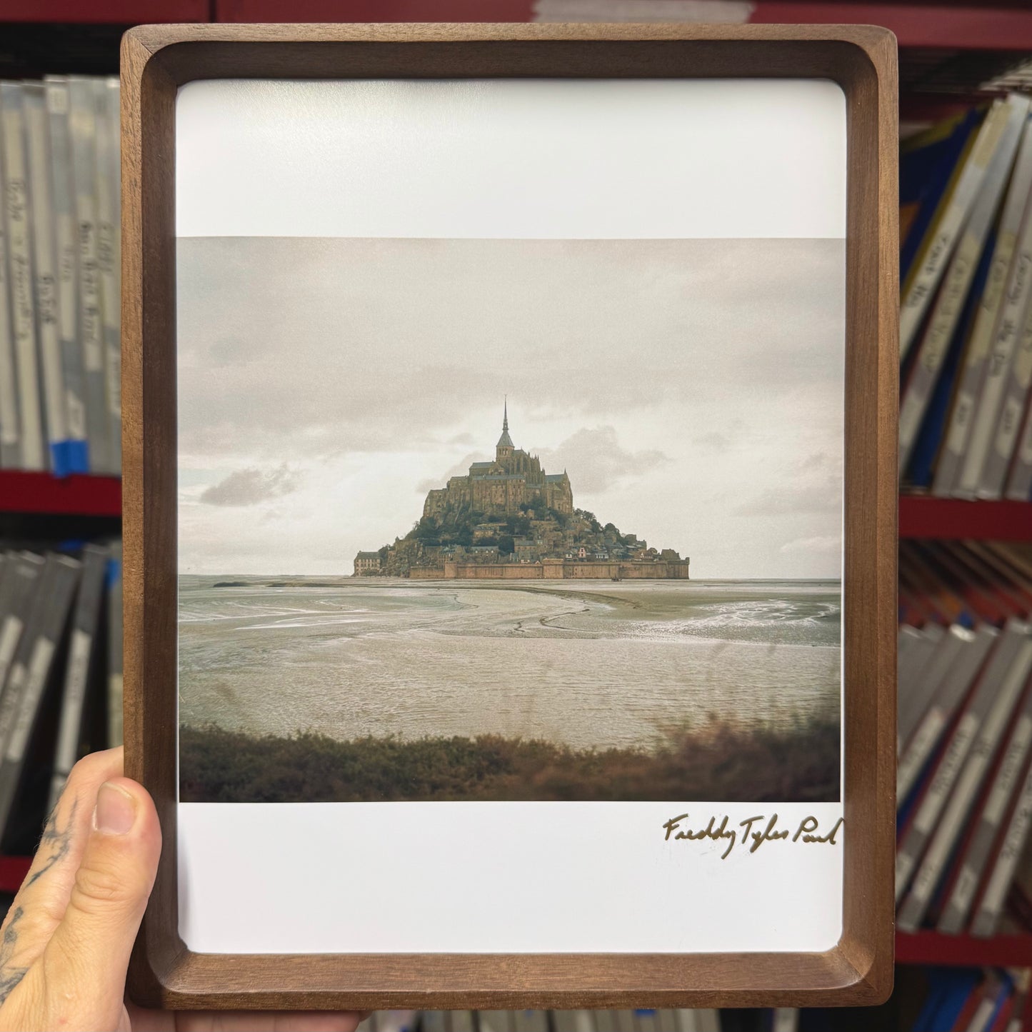 Framed photograph of a castle on an island held by a person.
