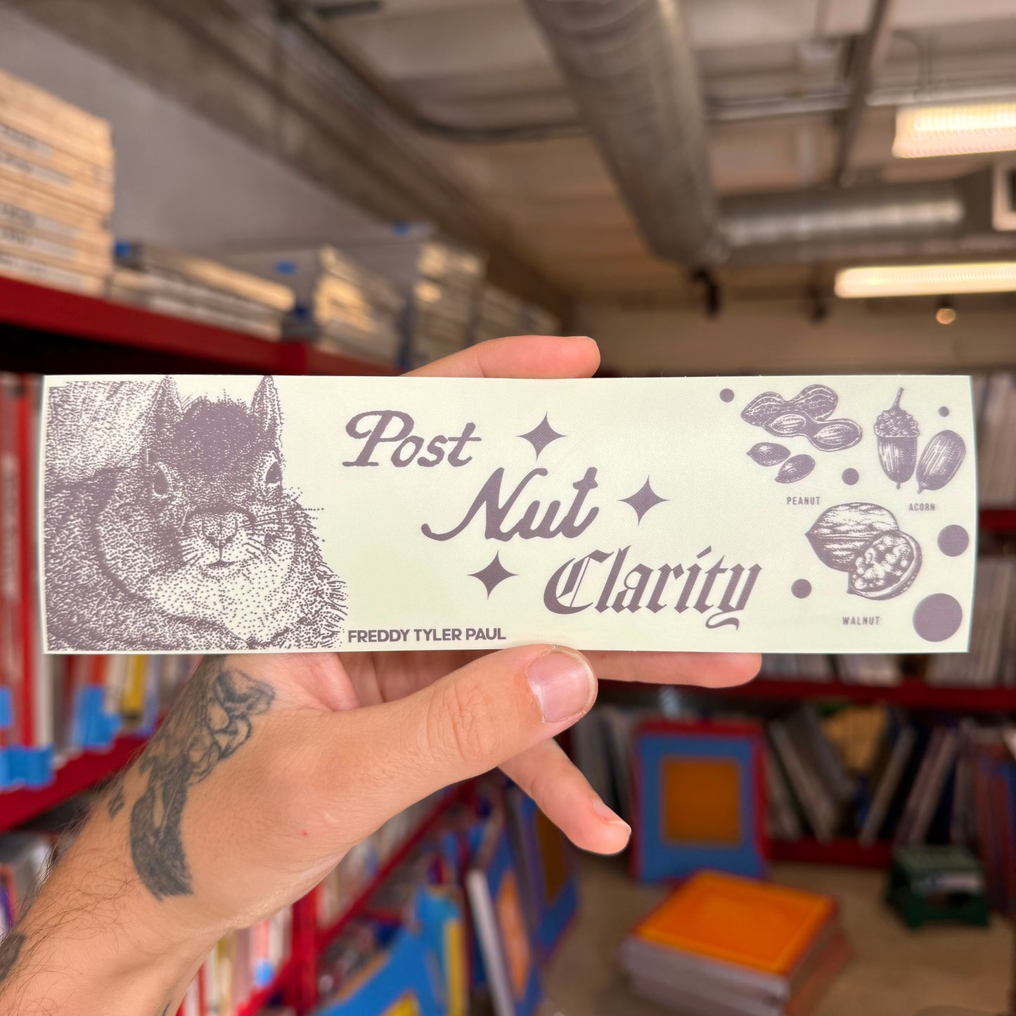Hand holding a product labeled 'Post Nut Clarity' with a squirrel illustration in a store setting.