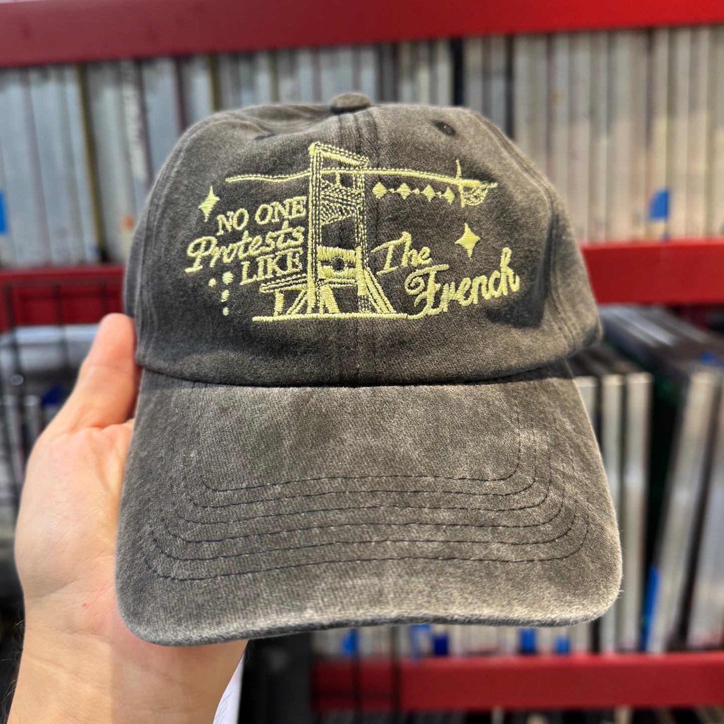 Gray cap with yellow text held in front of a store background