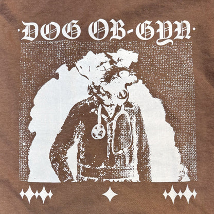 T-shirt with graphic of a person in a coat and stethoscope, labeled 'DOG OB-GYN', on a brown background.