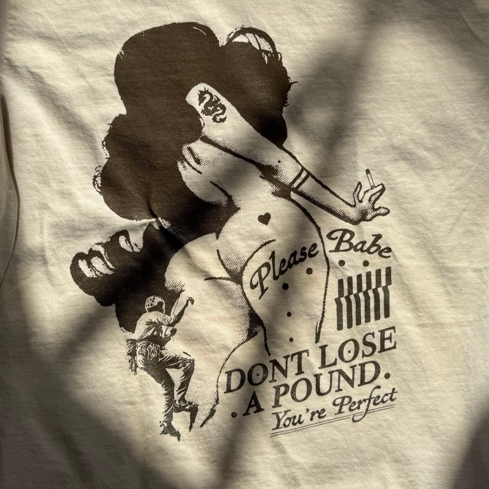 T-shirt with a graphic design of a woman and text on a beige background
