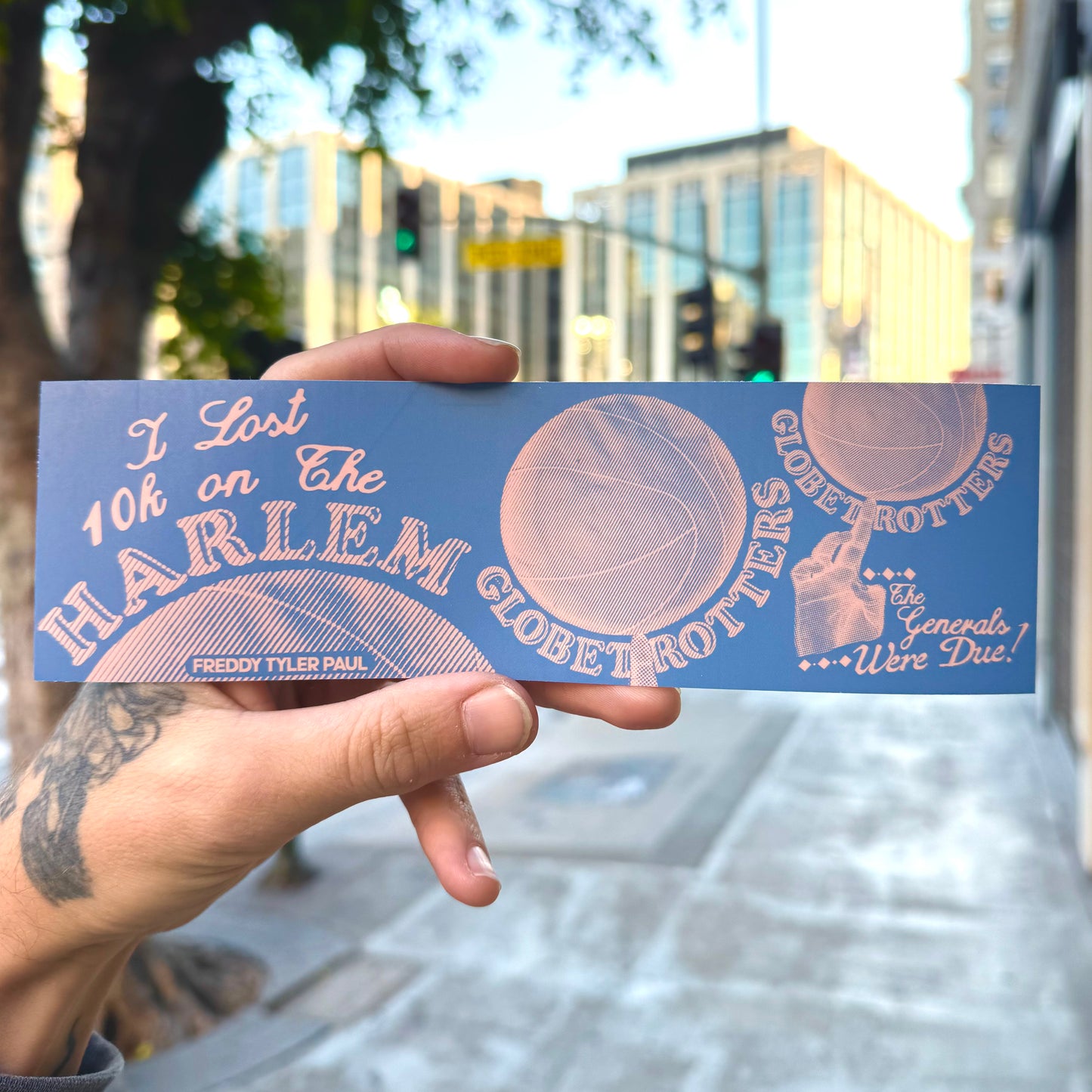 Hand holding a Harlem Globetrotters promotional card with cityscape in the background