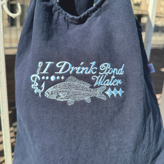 Navy blue sleeveless shirt with 'I Drink Pond Water' text and fish graphic on a hanger.