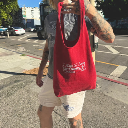Person holding a red tote bag with text on a street