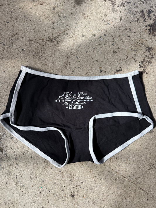 Black underwear with white text on a concrete surface