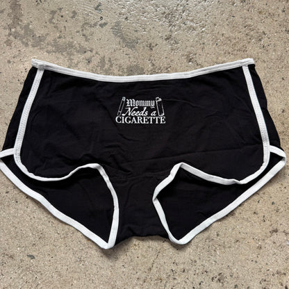 Black shorts with white trim and text on a concrete surface