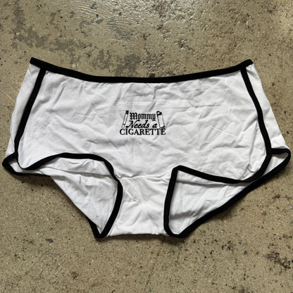 White underwear with black trim and text on a concrete surface