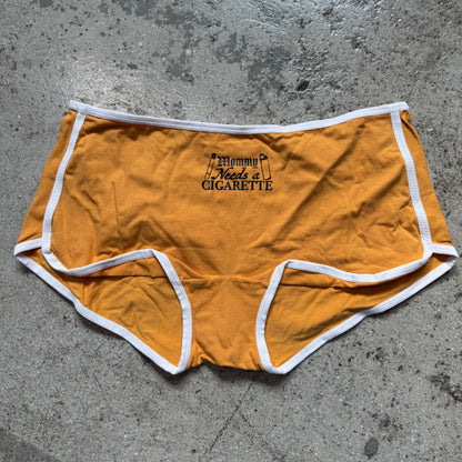 Mustard yellow shorts with text on a concrete surface