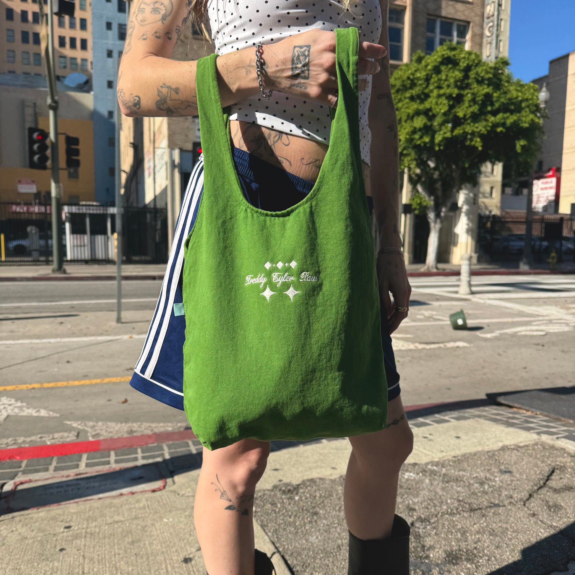 Person holding a green reusable bag on a city street