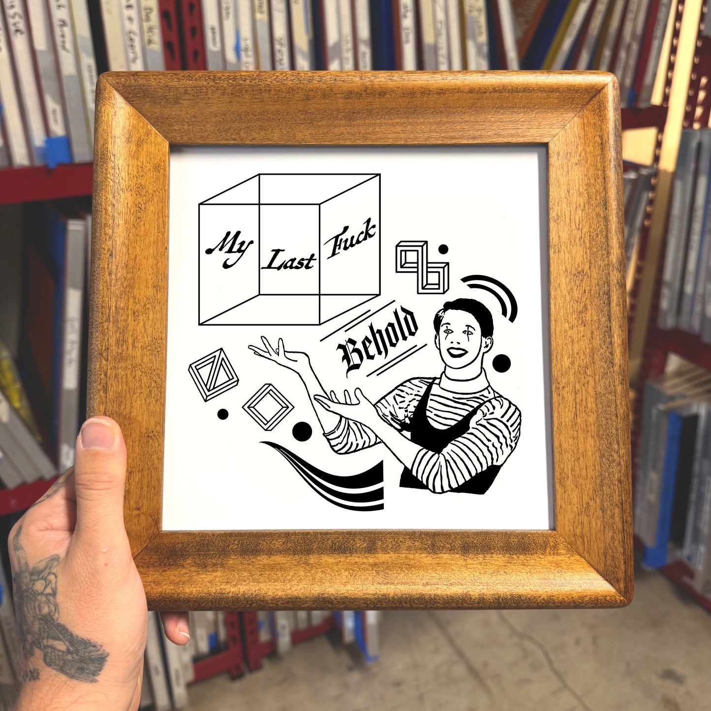 Framed black and white illustration held in front of a bookshelf.