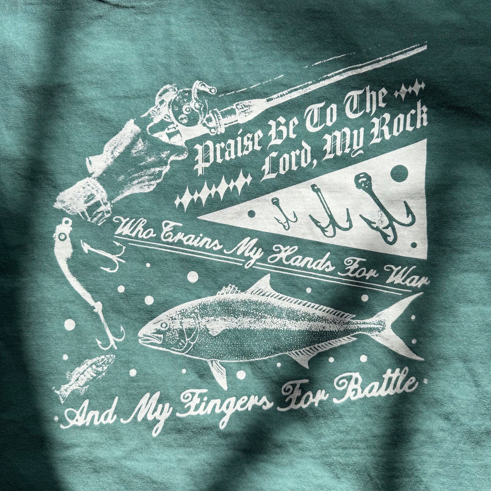 Teal t-shirt with white graphic design and text on a dark background