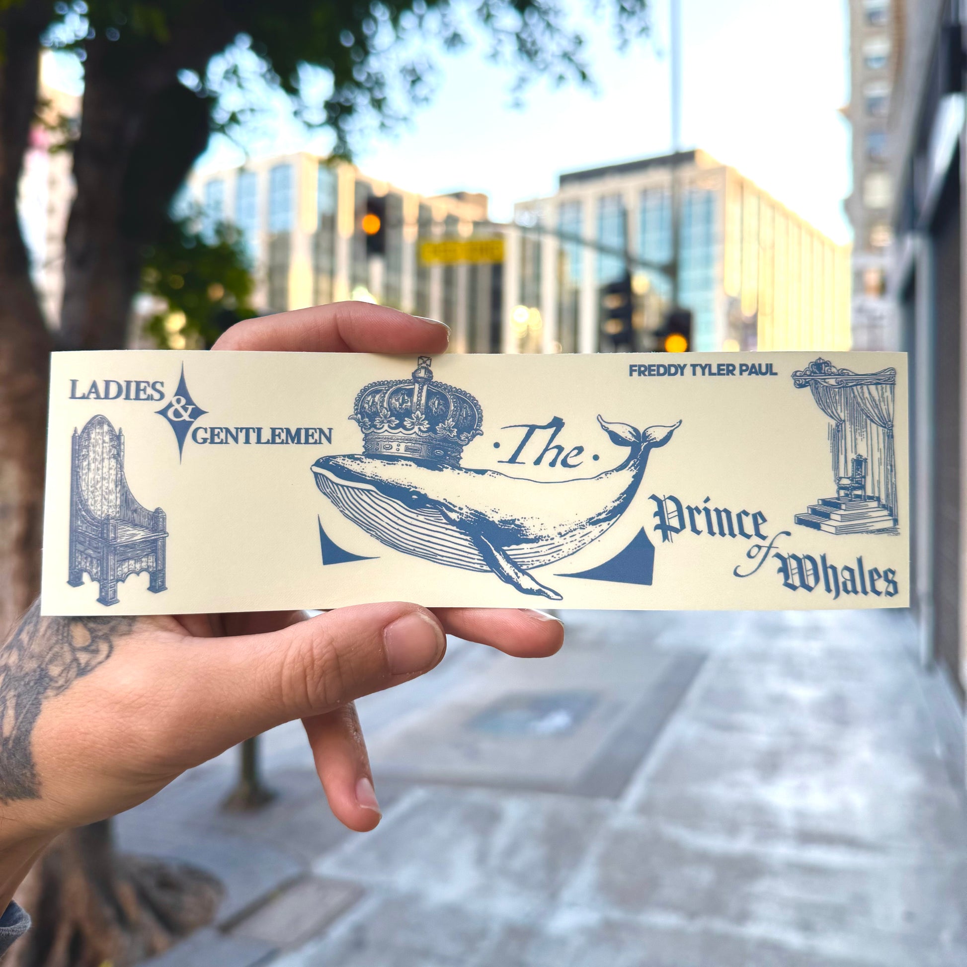 Hand holding a card with blue illustrations and text in an urban setting