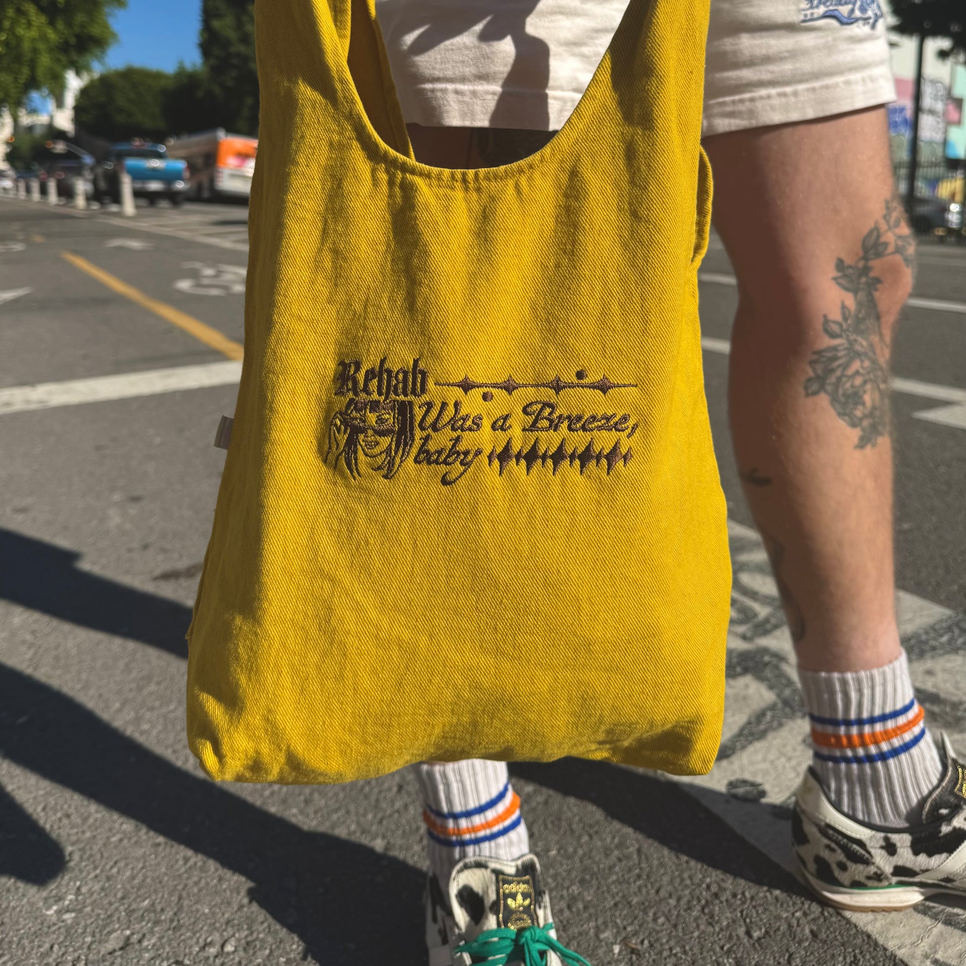 Person holding a yellow tote bag with text on a street.