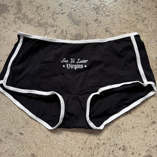Black underwear with white text on a concrete surface
