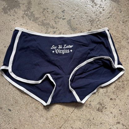 Navy blue shorts with white trim and text on a concrete surface