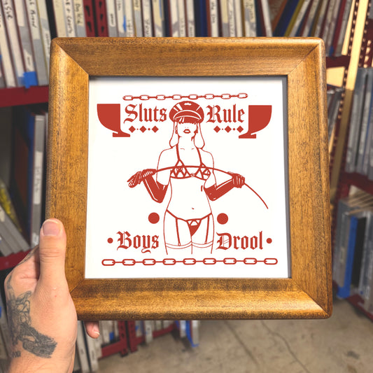 Framed poster with red and white design held in front of a bookshelf.