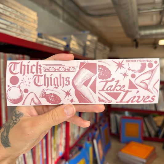 Hand holding a pink and white sticker with text and graphics in a bookstore setting
