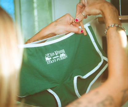 Green underwear with text held by a person, with a blurred background