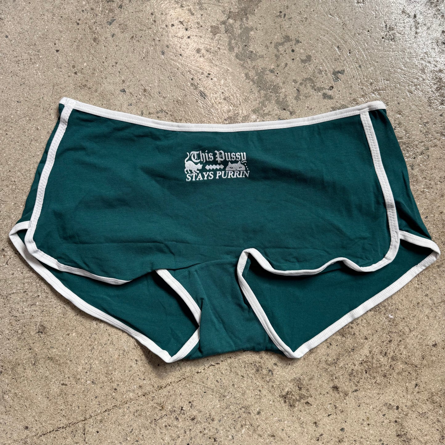 Green shorts with white trim on a concrete surface