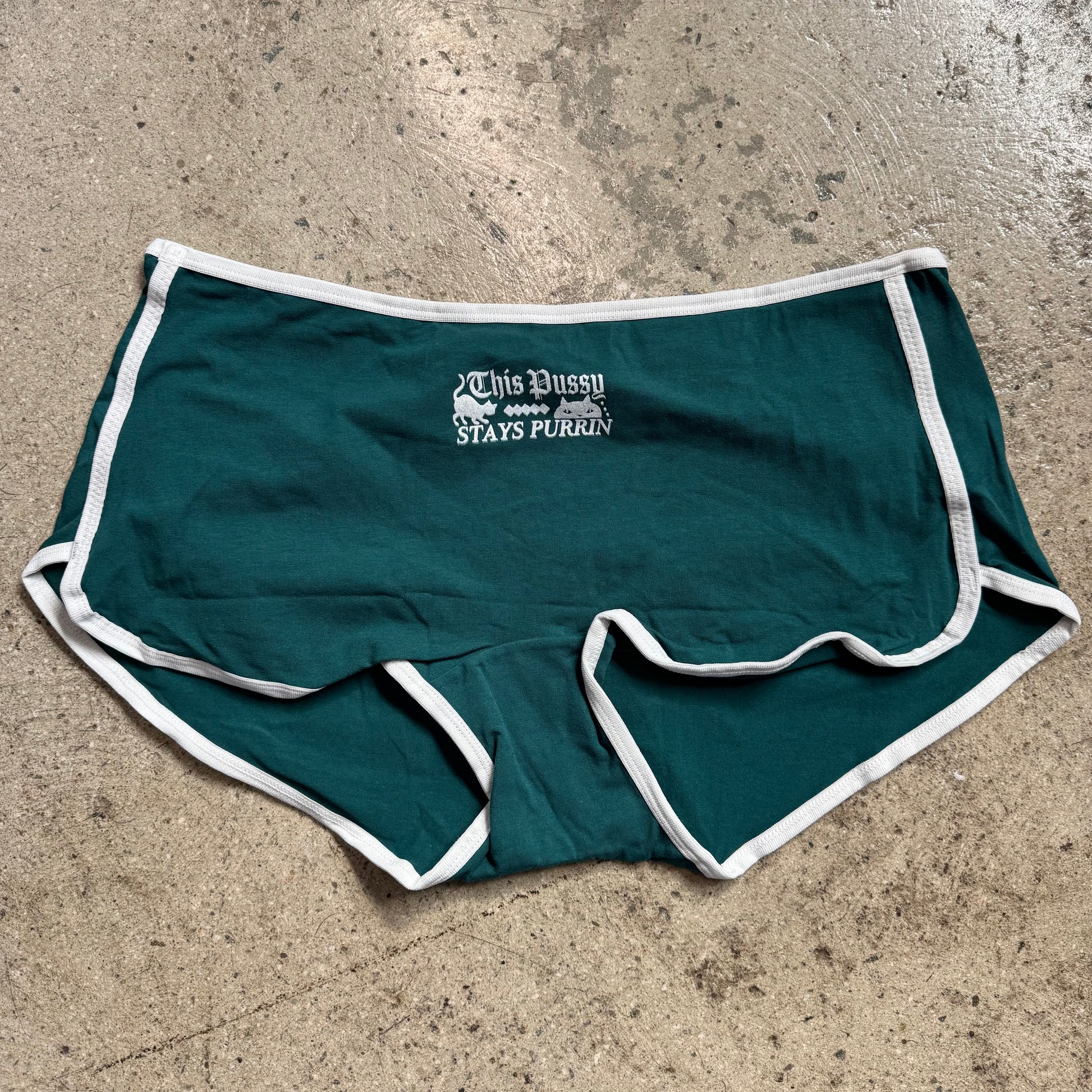 Green shorts with white trim on a concrete surface