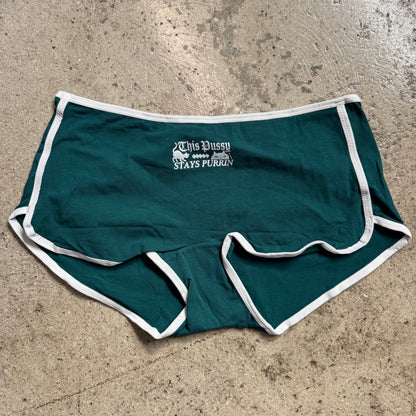 Green shorts with white trim on a concrete surface