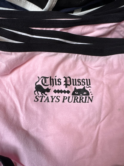 Pink shirt with black text and graphic design on a plain background