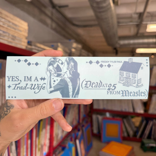 Hand holding a printed card with text and illustrations in a bookshelf setting