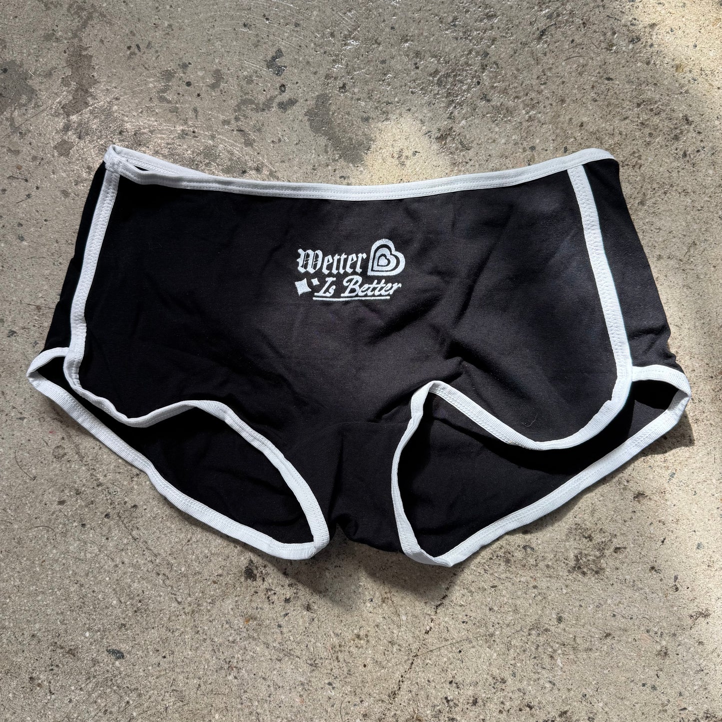 Black athletic shorts with white trim on a concrete surface