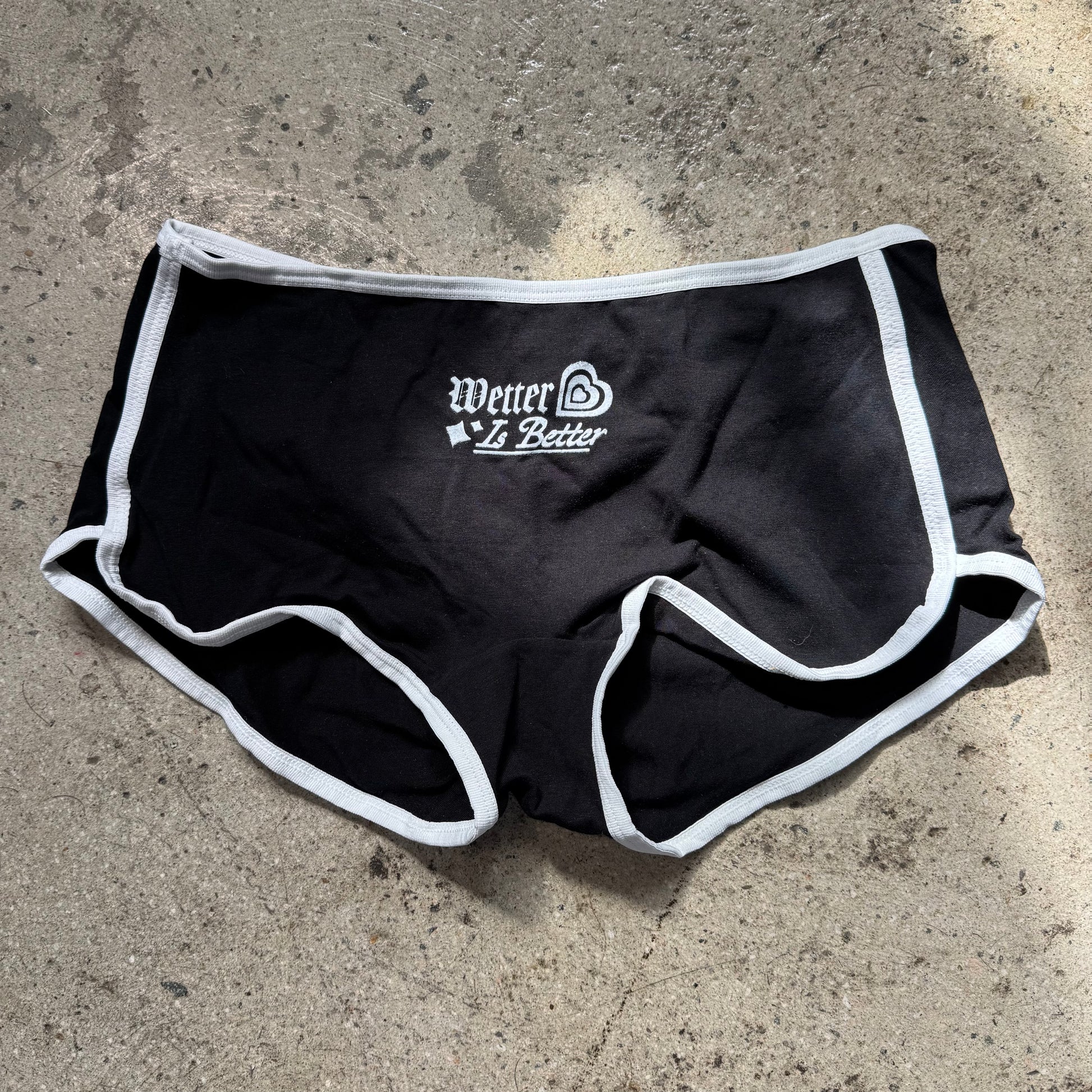 Black athletic shorts with white trim on a concrete surface