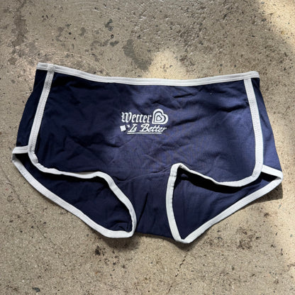 Navy blue athletic shorts with white trim on a concrete surface