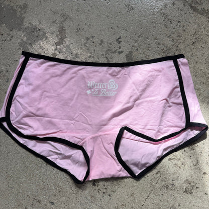 Pink underwear with black trim on a gray concrete surface