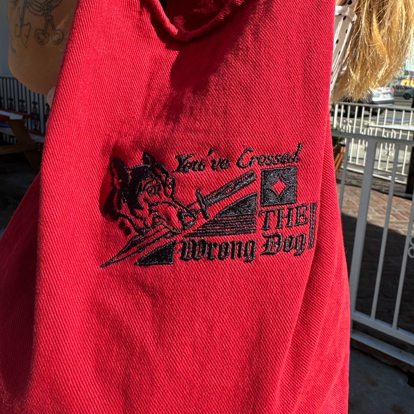 Red hoodie with black graphic and text 'You've Crossed THE Wrong Dog!' held by a person outdoors.