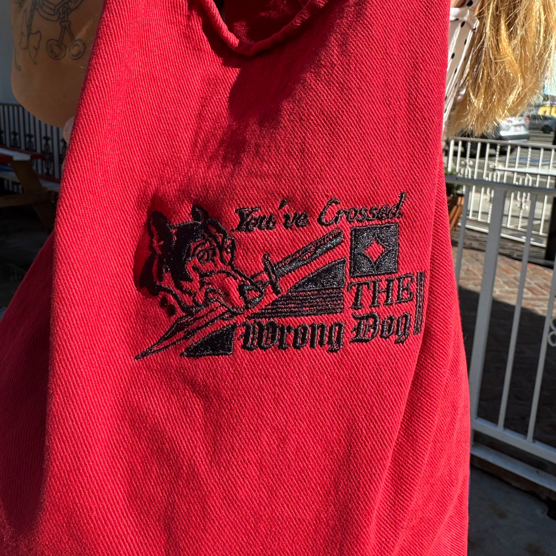 Red hoodie with black graphic and text 'You've Crossed THE Wrong Dog!' held by a person outdoors.