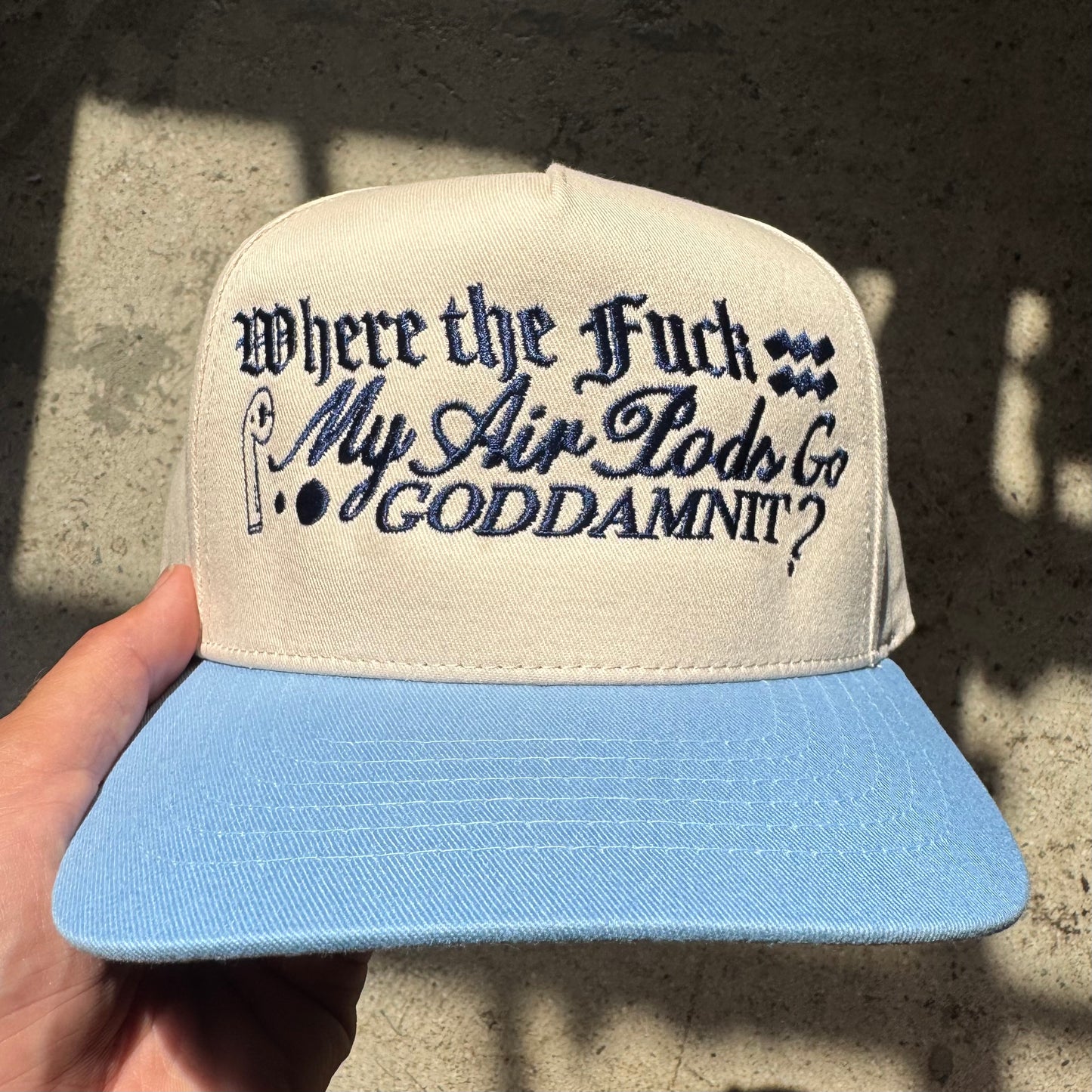 Cap with text held by a hand against a textured wall background