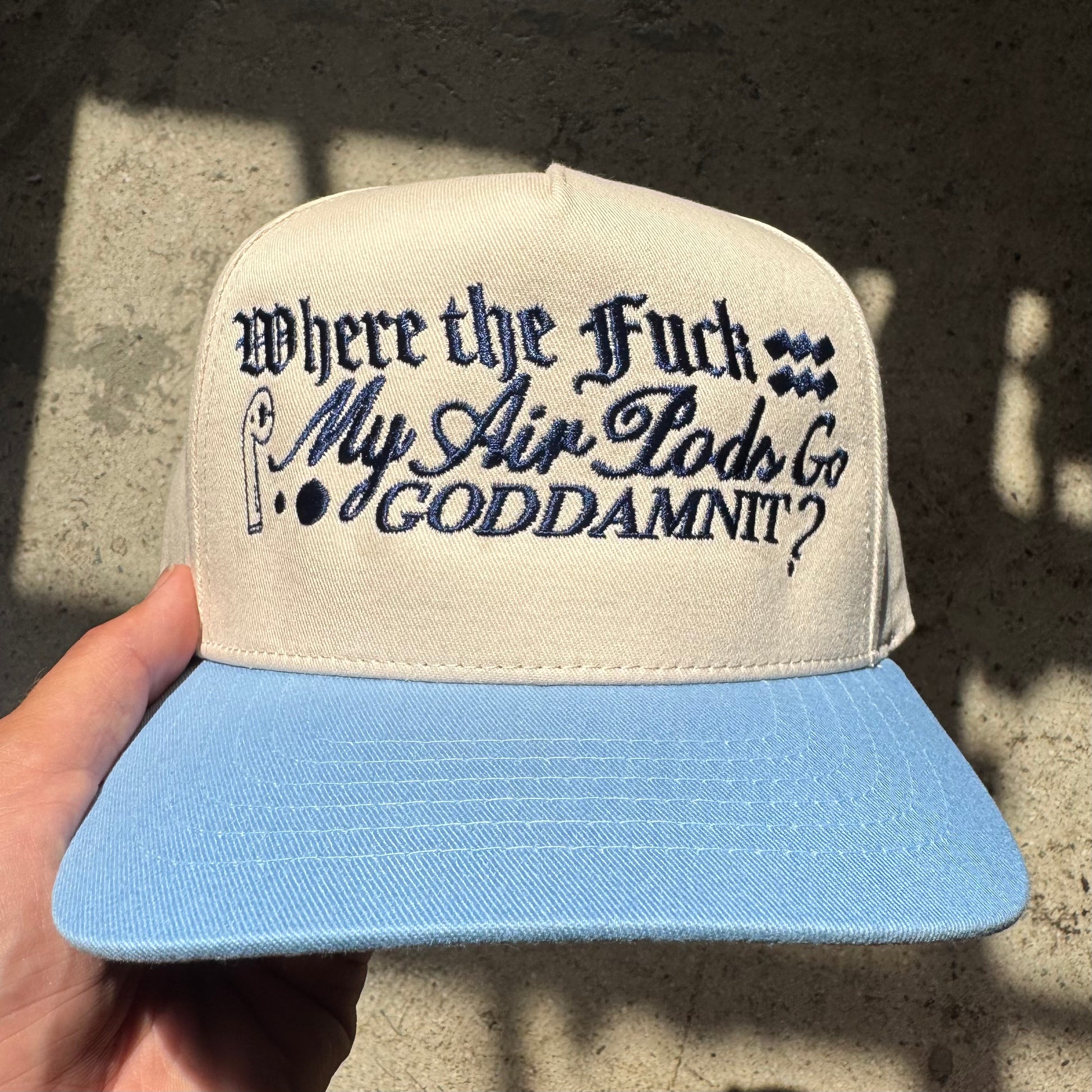 Cap with text held by a hand against a textured wall background