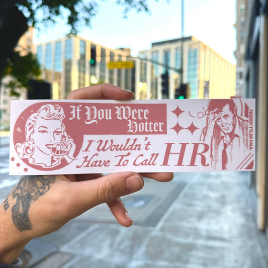 Hand holding a humorous sticker with text and graphics in an urban setting