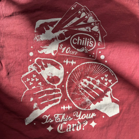 Red shirt with white graphic design featuring playing cards and text, including 'Chili's' branding.
