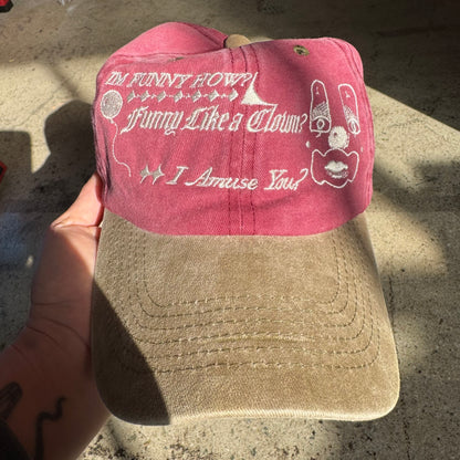 Pink and beige cap with text and graphics on a concrete surface
