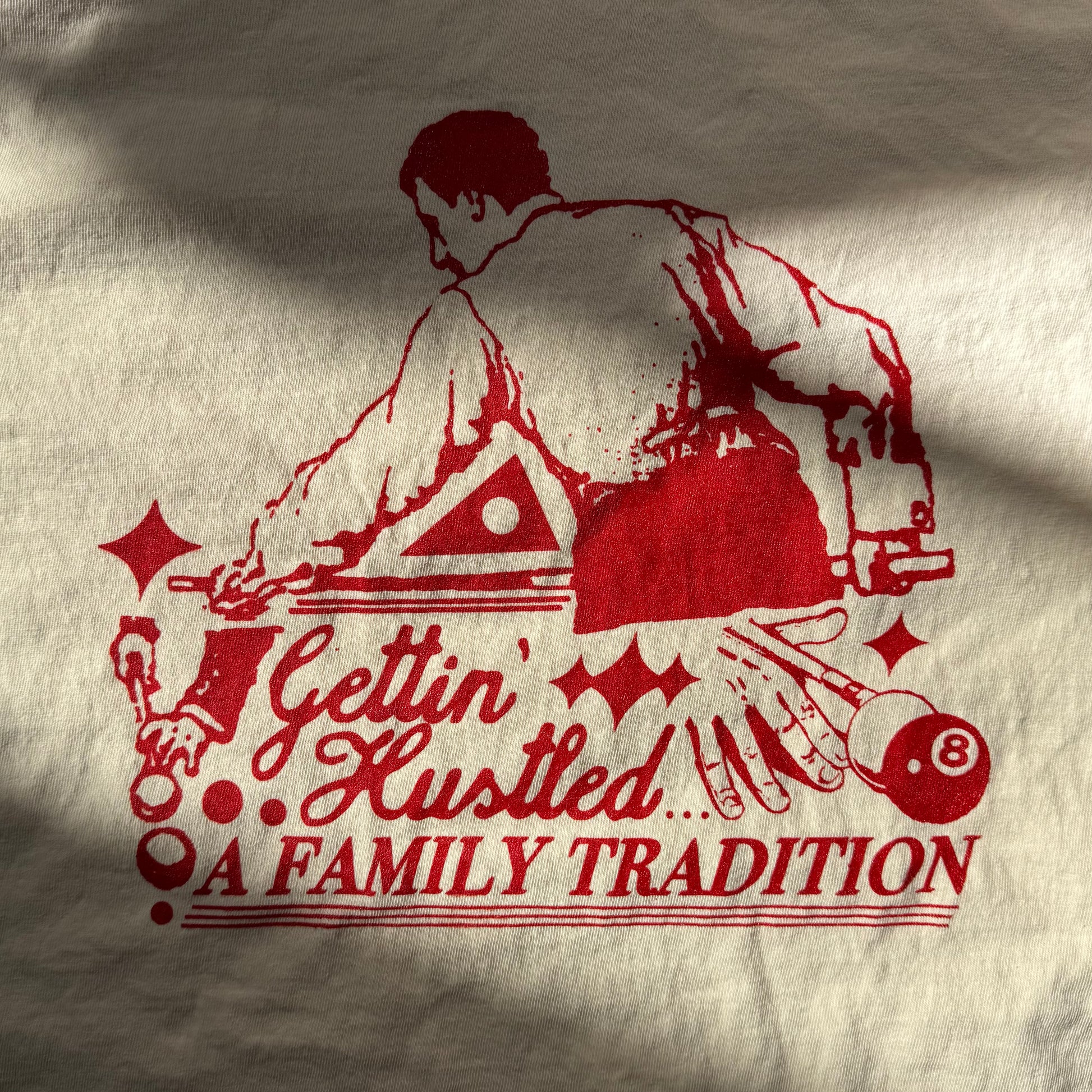 Red graphic of a man playing pool with text 'Gettin' Hustled... A Family Tradition' on beige fabric.