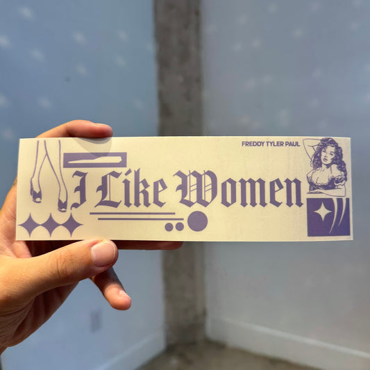 Hand holding a bumper sticker with text and graphics against a light blue wall.