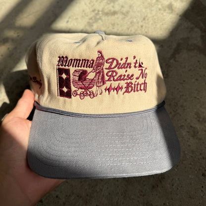 Cap with text and graphic held by a hand on a concrete surface