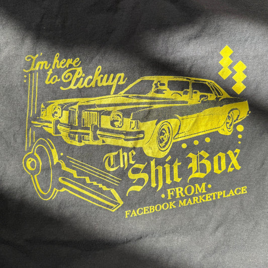 Gray t-shirt with yellow graphic of a car and text on a dark background