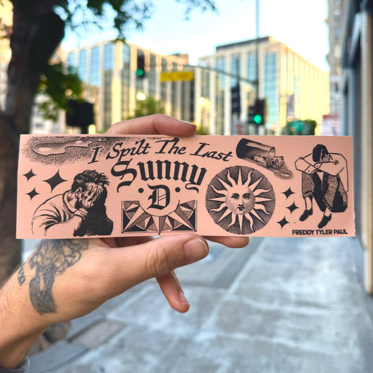 Hand holding a pink bumper sticker with black graphics and text in an urban setting