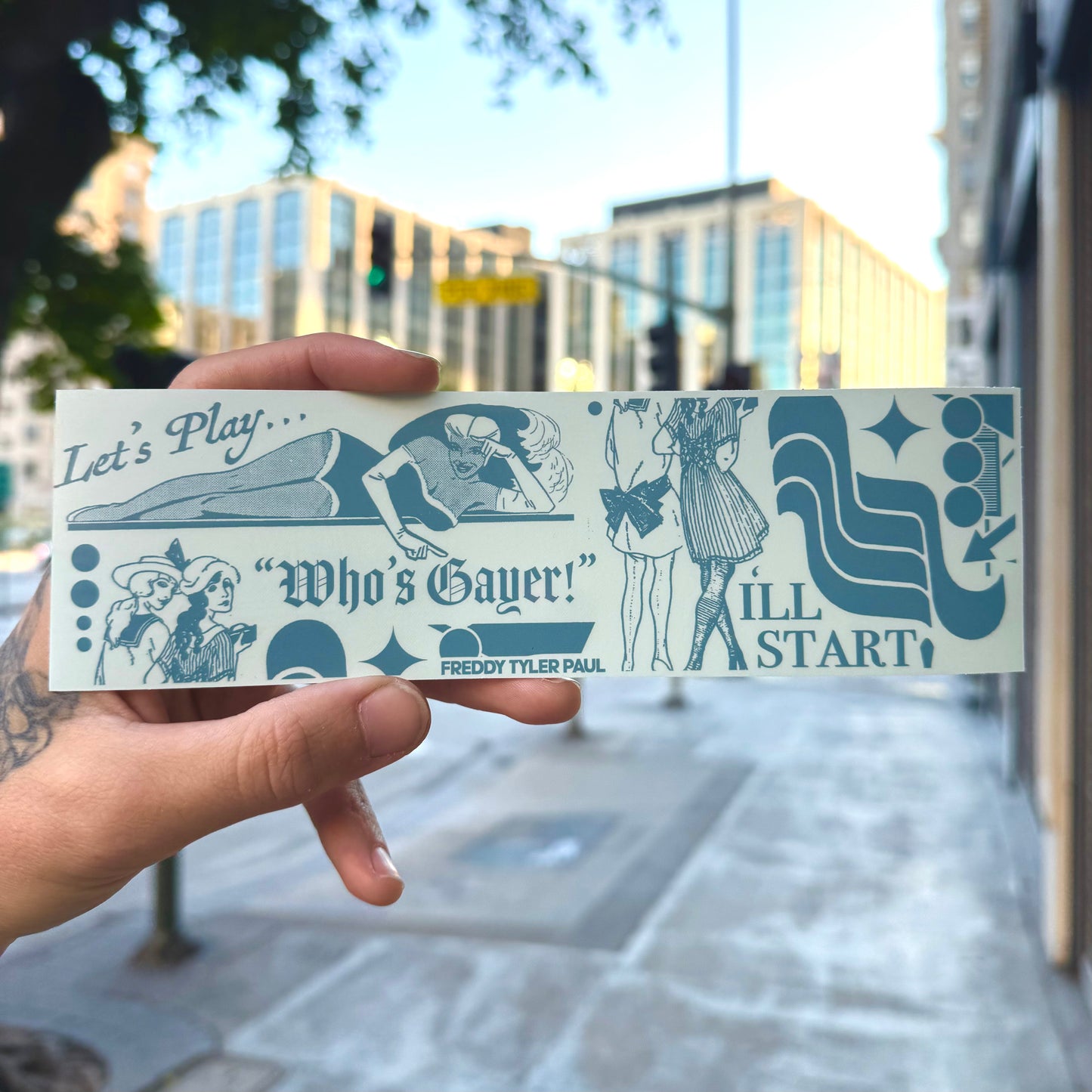 Hand holding a sticker with text and graphics outdoors