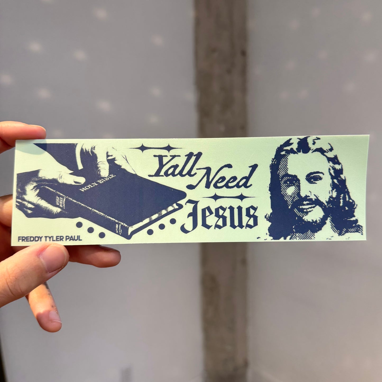 Sticker with 'Yall Need Jesus' text and a portrait of a person, held against a neutral background.